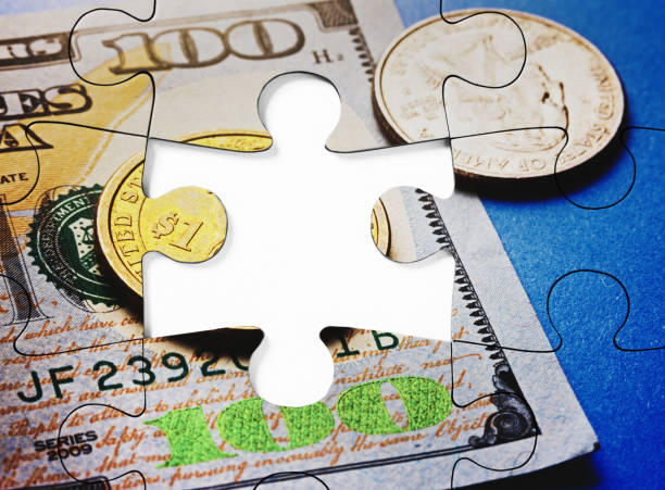 istock Jigsaw puzzle, depicting US money in cash and banknotes, complete except for one missing piece 1408710976