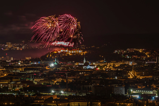 Fireworks over the night city of Brno in the Czech Republic in Europe. Above the city are different colored shapes of flares.