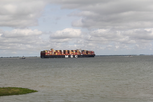 Hulst, Holland - jul 9, 2022: a big cargo ship is sailing in scheldt river at the dutch coast towards antwerp