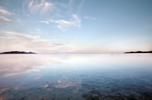 Rear view of a male contemplating view from above of Mediterranean sea in pink orange sunset lights with the hills of Oludeniz in Turkey