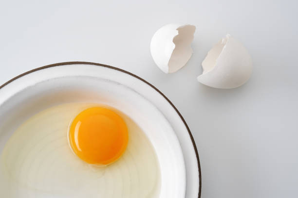 White broken egg with a yolk in a white plate. White  broken egg with a yolk in a white plate. Cracked egg, eggshells with yolk on white background. Shallow depth of field egg white stock pictures, royalty-free photos & images