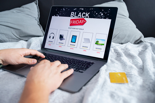 Close up of unrecognizable man usong laptop and credit card to make a online purchase of electronics on sale.Black Friday sale.