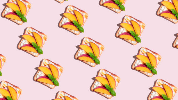 istock Pattern of toasted bread with peach and basil on pink background. 1408727431