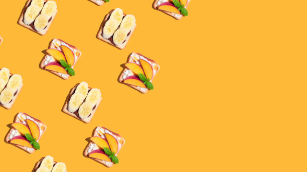 istock Set of toasted bread with peach and banana on yellow background. Pattern 1408727498