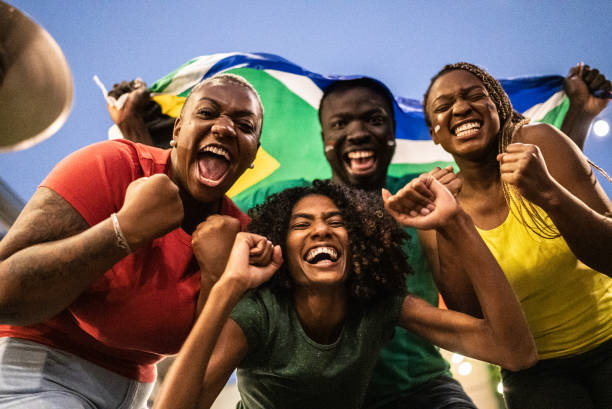 ritratto di amici che festeggiano con la bandiera sudafricana all'aperto - lega di calcio foto e immagini stock