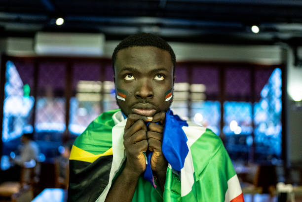 istock Young man watching sports team in a bar 1408727978