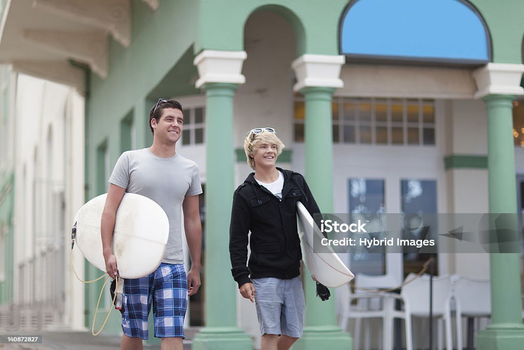 Teenage boys carrying surfboards  16-17 Years Stock Photo