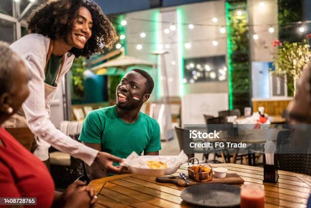 Waitress Serving French Fries To Sports Fans Friends In A Bar Stock Photo - Download Image Now