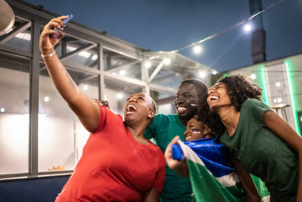 istock Sport fan friends taking a selfie using mobile phone in a bar 1408728812