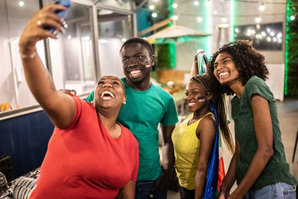 istock Sport fan friends taking a selfie using mobile phone in a bar 1408728818