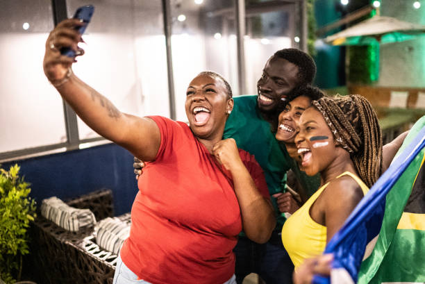 istock Sport fan friends taking a selfie using mobile phone in a bar 1408728881