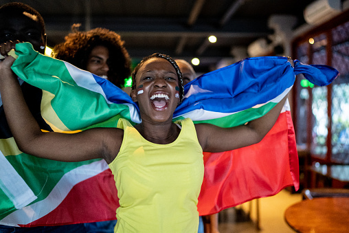 Young woman holding South African flag and celebrating