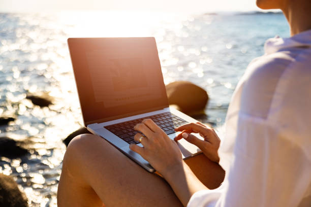 istock Unrecognizable female freelancer working on laptop, from the beach 1408730741