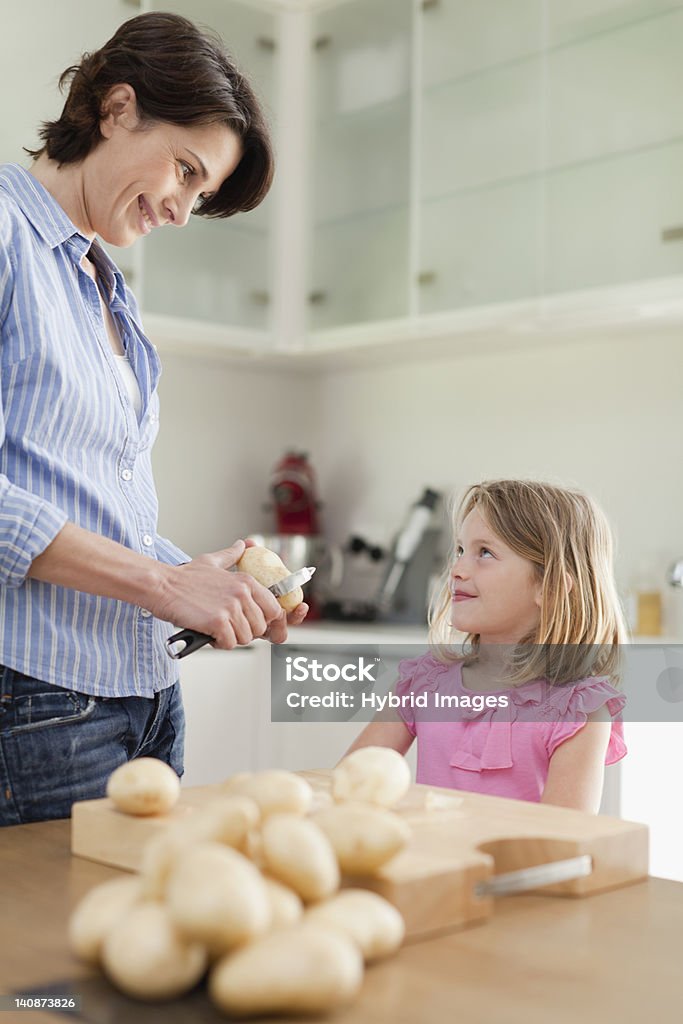 Mother helping daughter peel potatoes  Prepared Potato Stock Photo