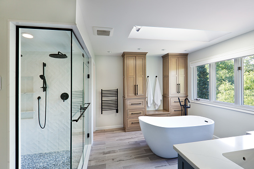 A contemporary modern bathroom design. featuring a freestanding bathtub and a glass shower stall