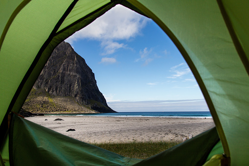 view from inside the tent to the outside like a window with beach, ocean and mountains on lofoten islands