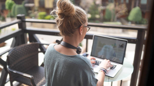 Empresária sentada sozinha e digitando em seu laptop trabalhando durante suas férias - foto de acervo