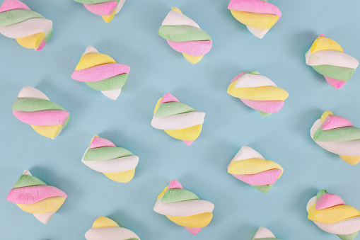 Multi colored marshmallow sweets on teal blue background