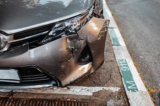 A close-up picture of a parked car that was damaged in a car crash.