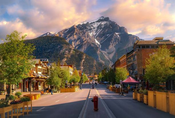 Sunrise Clouds Over A Mountain Road Through The Town Of Banff A colourful sunrise sky over a road leading through the town of Banff in the summertime. banff national park photos stock pictures, royalty-free photos & images