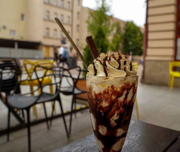 Whipped cream with chocolate syrup and ice cream dessert in a long tall glass cup