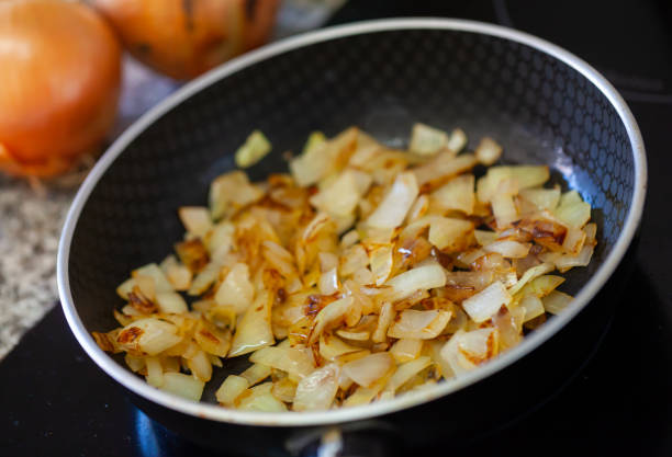Chopped onions are fried in a black pan, cooking and kitchen concept