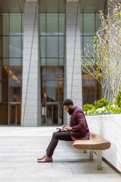 Black businessman checking e-mails in front of the office building