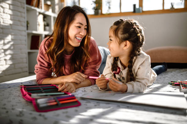istock Little girl playing with mother, using felt pen for drawing 1408769941