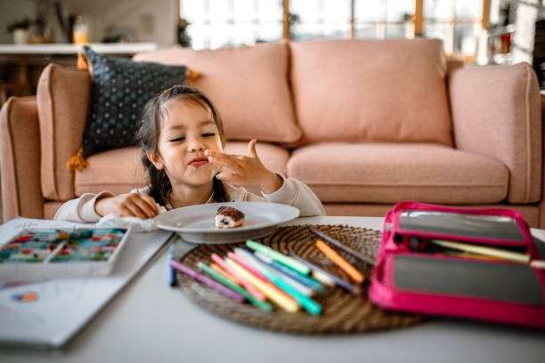 istock Cute little girl eating chocolate filled doughnut 1408770133