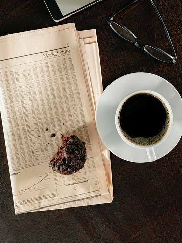 Looking down on a coffee cup and newspaper on desktop