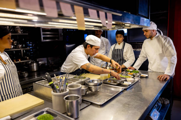 istock Chef working at a restaurant and showing his team how to prepare a plate 1408797965