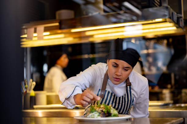 istock Female cook decorating a plate while working at a commercial kitchen 1408797979
