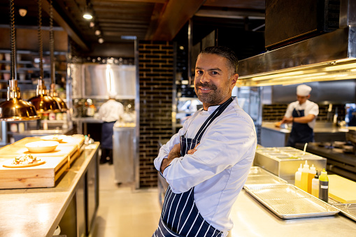 Portrait of a successful chef looking happy in the kitchen at his restaurant and smiling at the camera