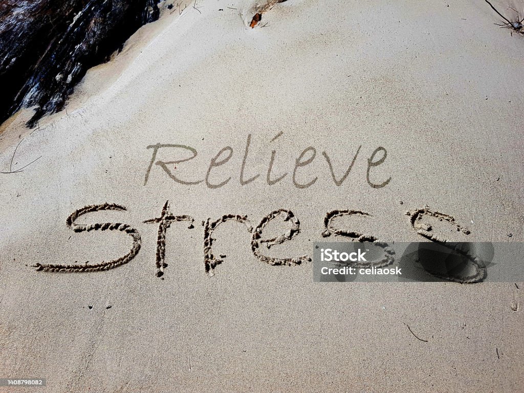 The words Relieve Stress are written on sandy beach The words Relieve Stress are written on sandy beach. Stress awareness concept. Sand Stock Photo