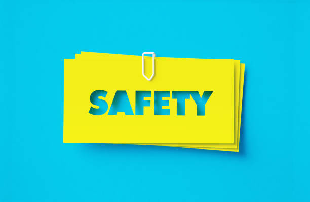 Safety written cut out yellow adhesive notes sitting on blue background. Horizontal composition with copy space.