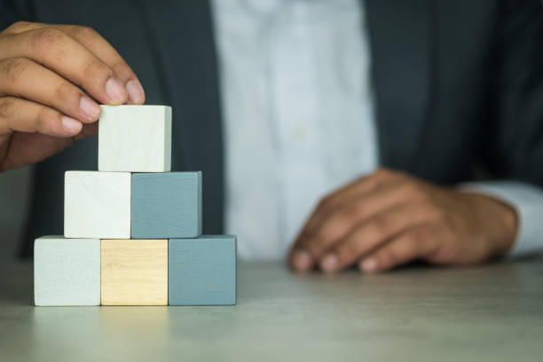 istock Hand putting wood cube block on top pyramid. 1408801887