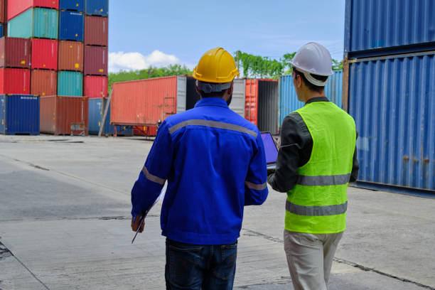 istock Two male workers work at a logistics terminal with many stacks of containers. 1408804169