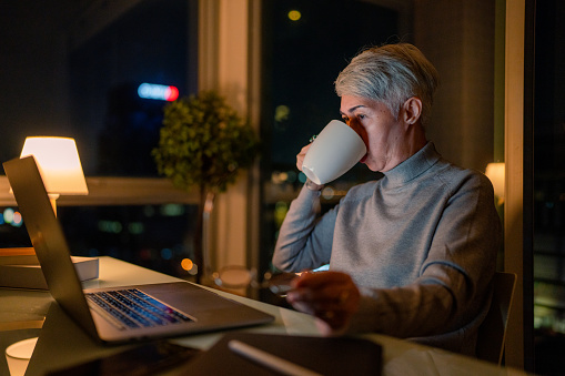 Asian senior stress out with project business plan on computer at home office at night.
