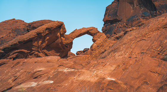 The Arch rock in Valley of Fire is a famous landmark in this red rock desert landscape in Nevada, USA. Seen a hot summer day.