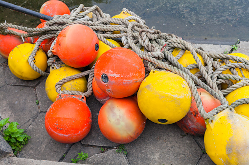 Yellow and orange buoys stacked on the pier