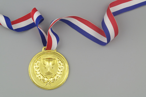Gold medal with multicolored ribbon on blue background, copy space for text.