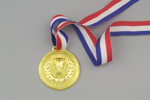 Gold medal with multicolored ribbon on blue background, copy space for text.