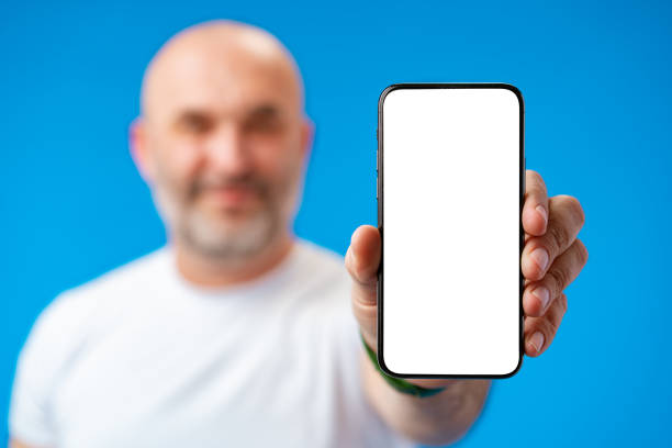 istock Middle-aged man showing blank smartphone screen with copy space against blue background 1408818532