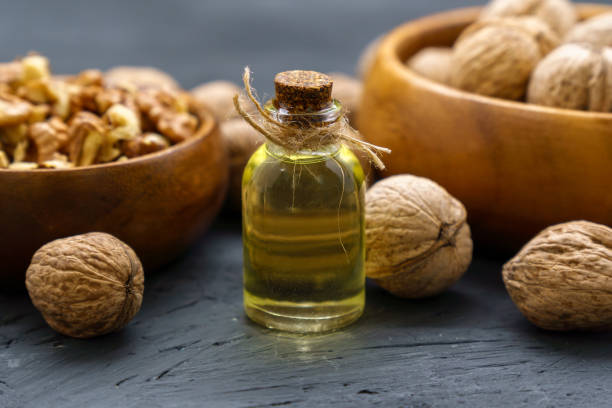 istock Glass bottle with essence, raw walnut peeled and in their shells, rustic style, selective focus 1408820382