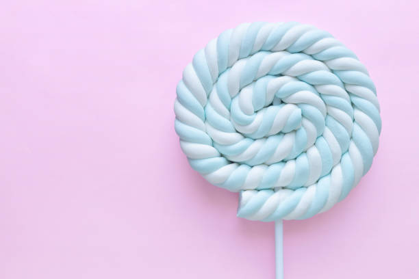 pastel blue and white spiral marshmallow lollipop on pastel pink background