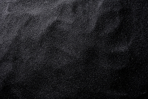 Overhead shot of black sand texture background.