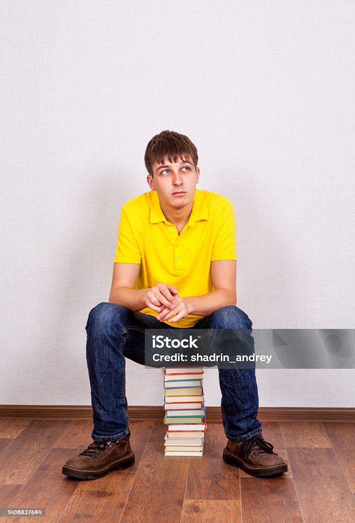 Young Man with a Books Pensive Young Man with a Books on the Floor in the Room 25-29 Years Stock Photo