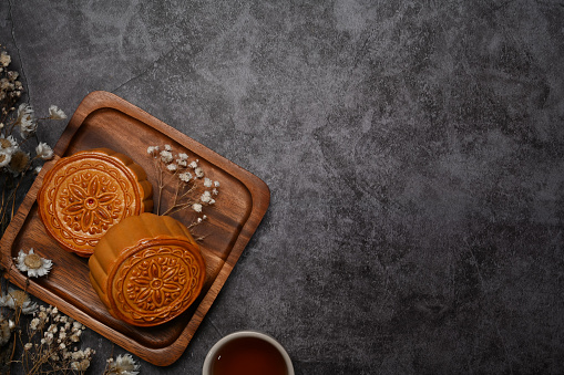 Above view Chinese moon cake for Mid Autumn festival and tea on rustic stone background with copy space.