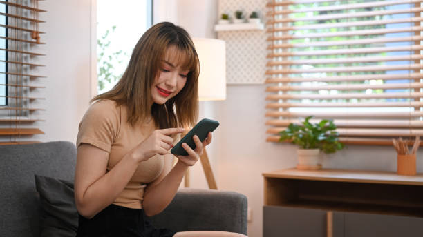 istock Pretty young woman using mobile phone for chatting with friends while resting in comfortable couch at home. 1408827725