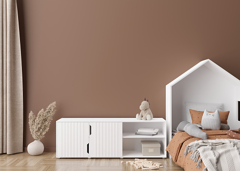 Empty brown wall in modern child room. Mock up interior in scandinavian style. Copy space for your picture or poster. Bed, sideboard, pampas grass, toys. Cozy room for kids. 3D rendering.